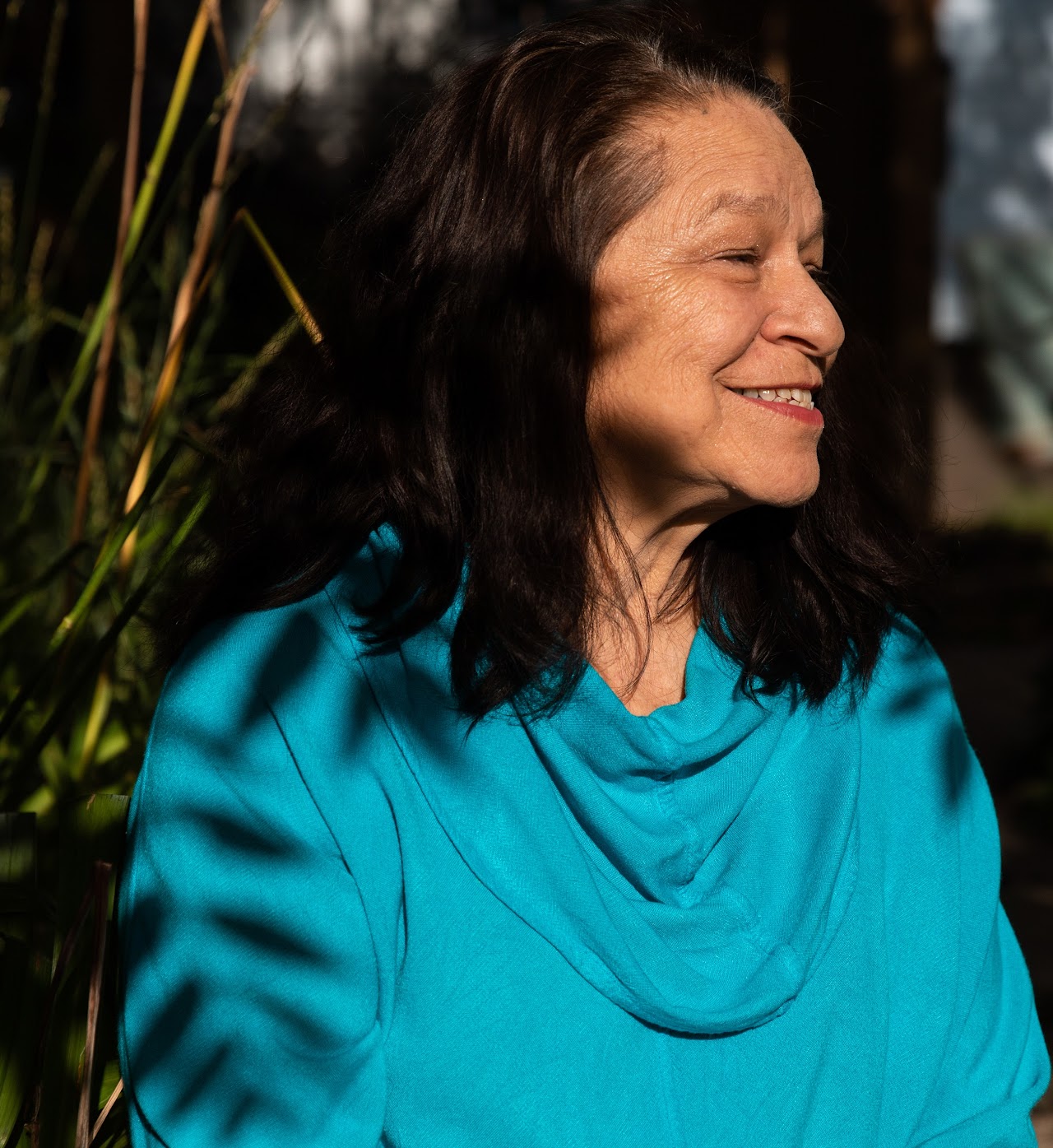 Photo of Marcie Rendon smiling, wearing a turquois colored shirt