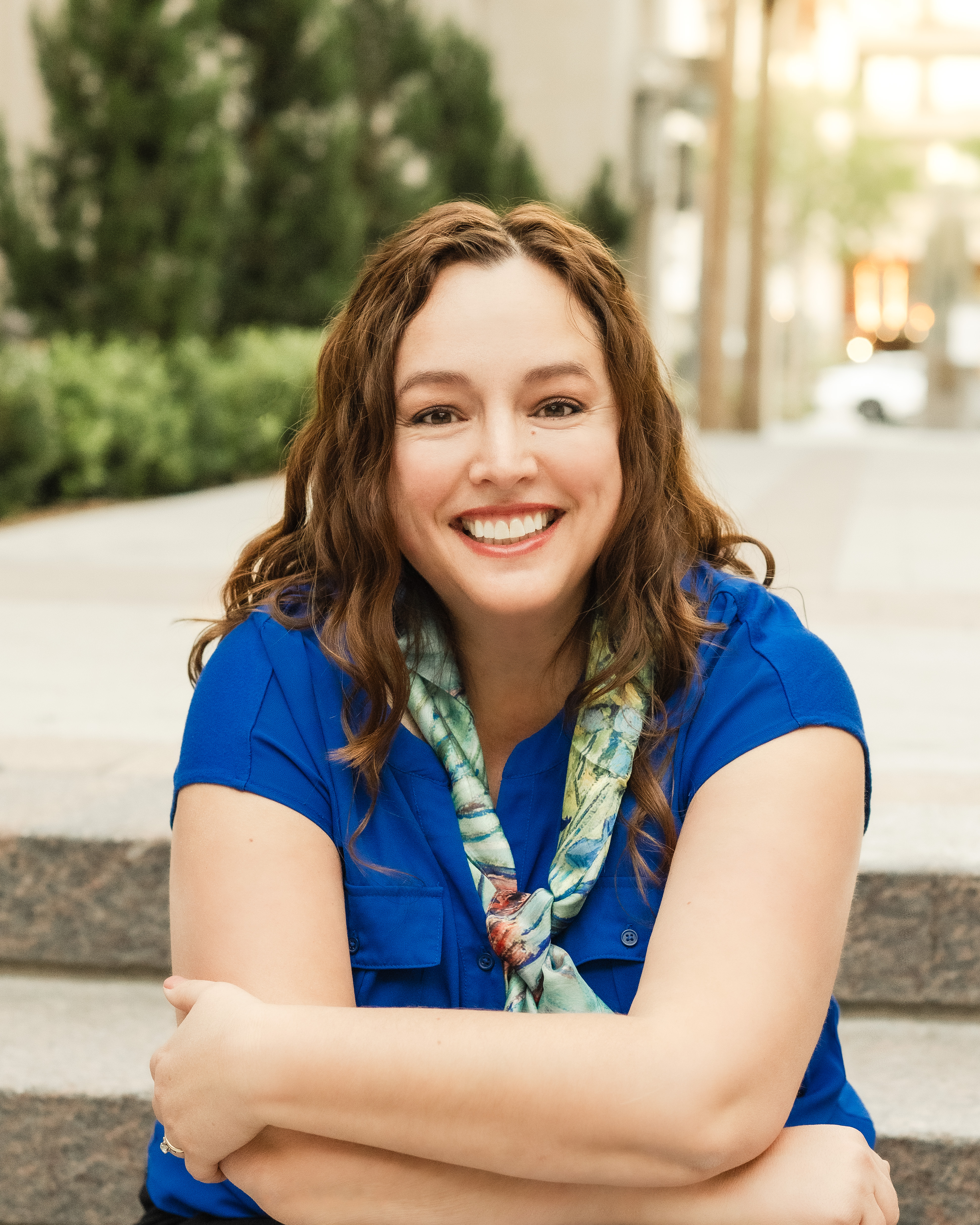 Amanda Skenandore outdoors, seated on steps and smiling at camera