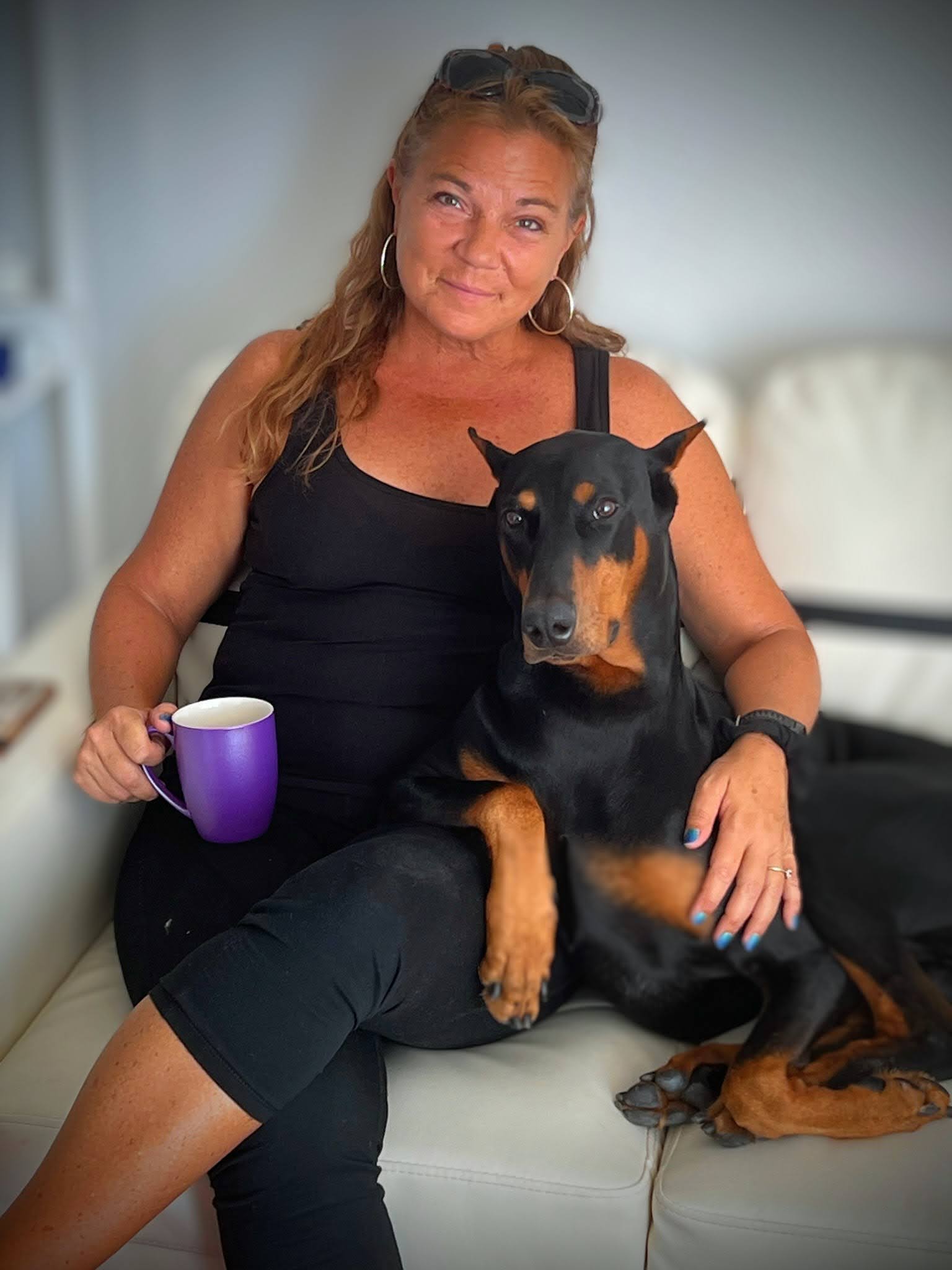photo of Kirsten "Kiki" Ringer and her Doberman, Seven, sitting on a couch